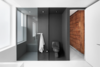 Modern home with Bath Room. A original hemlock wood wall clads the corridor leading to the bathroom. Just inside, the dark gray epoxied shower area (with a Cimarron Kohler toilet) forms a solid contrast to the white walls and floors. Photo of A Futuristic Apartment with a Glass-Enclosed Bedroom