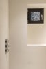 Similar to the kitchen, white materials and finishes are favored in the home's bathrooms. White limestone is complemented by Ikea cabinets, counters, sinks, and taps. Square casement windows provide a strong focal point and help bring natural light into the space. Photo 9 of Ferrum House modern home