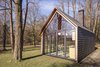 Modern home with Exterior, Cabin Building Type, Wood Siding Material, Gable RoofLine, Glass Siding Material, and Shingles Roof Material. With one side of the house closed off, views are directed through the glazed south and west facades to the grassy clearing beyond. "We planted tens of thousands of blue bells and lots of rhododendrons," Oostenbruggen says of the green space. "The setting developed over time." Photo 3 of Utrecht Cabin