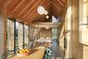 Modern home with Kitchen, Wood Counter, Pendant Lighting, and Wood Cabinet. The house's open plan is neatly divided into public and private spaces, with the front containing the kitchen and living areas and the back holding the bedroom and bath, overhung by a small mezzanine. A hidden wooden panel can be drawn closed between the two sections for greater privacy. Photo 5 of Utrecht Cabin