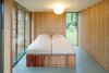 Modern home with Bedroom, Bed, and Ceiling Lighting. Light breaks through the bedroom's north wall through a vertical window that cuts from the floor up past the second floor mezzanine to the roof's ridgeline. The bed is custom. Photo 7 of Utrecht Cabin