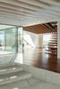 Modern home with Staircase and Wood Tread. The connecting area between the four houses has an open joisted pine ceiling that offers a masterful transition between the coarse, weathered exterior and the polished rooms—all lined with smooth Sucupira wood and white plaster board. “We wanted to make a clear contrast between the interior surfaces of the house and the corresponding exterior surfaces,” de Carvalho says. Photo 4 of House of Four Houses