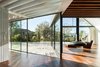 Modern home with Living Room, Hanging Fireplace, Medium Hardwood Floor, and Chair. In the living room, a central hanging fireplace offers warmth and ambience without blocking the view to the valley outside. “In certain autumn or spring nights, the clients may appreciate it on the outside with the windows open,” de Carvalho says. Photo 5 of House of Four Houses