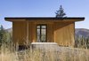 Modern home with Exterior, Cabin Building Type, Flat RoofLine, and Wood Siding Material. Deep eaves prevent the entrance from being buried in snow. The clients can see directly into the valley and mountains below. Photo of Simple Cabin Embraces Its Mountain Setting