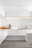 The stark white minimalist kitchen features quartz countertops, a Gessi Oxygene tap, a 1810 Company Zenuno sink, and energy-efficient Bosch appliances. Photo 6 of Ferrum House modern home