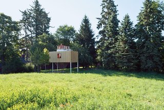 The polycarbonate interior is bounded by an exterior band of reclaimed white-cedar siding, open to the sky.