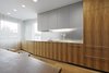 Modern home with Kitchen, Wood Cabinet, White Cabinet, and Medium Hardwood Floor. A wall of custom cabinets made with Paldao wood veneer defines the kitchen. "We wanted them to be as clean and minimal as possible but to have a warm texture," Slade says. "The aluminum countertop, resin upper cabinets, and satin mirror glass backsplash are designed to reflect light." Photo 2 of Modern Dream Penthouse in New York City Makes the Most of Natural Light