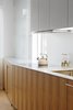 Modern home with Kitchen, Wood Cabinet, White Cabinet, and Cooktops. The countertop is a solid aluminum plate. The cooktop, hood, and dishwasher are Miele. Photo 3 of Modern Dream Penthouse in New York City Makes the Most of Natural Light
