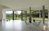 The 57-foot panoramic window was inspired by traditional "Engawa" houses in Japan. Koolhaas preserved its minimalistic aesthetic by camouflaging the supporting wood beam in white laminate and nestling it in the space just beneath the ceiling. He also kept the beam small by installing a tree-like column to help carry the weight of the second floor and roof. "The actual tree that was used for it came out of the garden," the architect says. "In this way, the small forest in the garden continues into the house." Photo 4 of Triangular House modern home