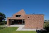 Modern home with Grass, Back Yard, Exterior, Brick Siding Material, and House. It's traditional among homes in the region to enter through their backdoor, seen here. The door leads directly to the living room. Photo of A Dutch Home that Plays with Traditional Brick Architecture