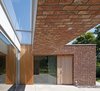 Just outside the entrance, the conventional masonry construction transforms from wall to ceiling, thereby creating a sheltered patio space. Photo of A Dutch Home that Plays with Traditional Brick Architecture modern home