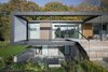 Located in Aarhus, Denmark, Villa R is a minimalist, serene structure clad in zinc panels. "The objective was to create a house that brings the forest inside through large glass panels—and create an ever-changing seasonal backdrop for the interior living spaces," stated the architecture firm, C.F. Møller, of the 3,200-square-foot abode. Photo of Villa R modern home