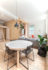 Carefully chosen furniture and fixtures make every square foot count. In the dining room, a Muuto Unfold pendant hangs above an Artek Aaldto dining table. The track lighting is by Masson for Light Comet. The living room features a gray Nook Sofa by Jardan and a red Eames Molded Plywood Chair that contrast playfully with the Baltic pine floors. Photo of A Tiny Apartment Renovation for a Growing Family in Melbourne modern home
