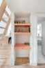 Whimsical salmon accents play favorably against the pine floors and plywood joinery. A ladder in the living room leads up to a mezzanine loft guest room while also creating a compact work nook below. Photo of A Tiny Apartment Renovation for a Growing Family in Melbourne modern home