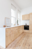 The kitchen features oyster gray Laminex countertops, an Astra Walker brass-plated sink, and a Miele oven. Photo of A Tiny Apartment Renovation for a Growing Family in Melbourne modern home