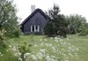 The architects replaced the existing orange cinder-block facade with plaster walls and Pomeranian pine wood shingles, put on a new thatched roof, and installed “stable door” windows. Nestled among pines and fruit trees, its traditional exterior belies the modern interior within. Photo of A Thatched Cottage in Denmark with a Modern, Space-Saving Interior modern home