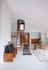 The architects installed plaster walls and a curved ceiling that lets in more light. Its circular design repeats in the entrance to the master bedroom, accessible by a ladder. Photo of A Thatched Cottage in Denmark with a Modern, Space-Saving Interior modern home
