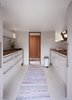 The kitchen cabinets and fixtures are all sourced from Swan Cuisines. The trashcan is by Vipp. The architects opted to install only a small stove with no oven, as the garden already has a fireplace. Photo of A Thatched Cottage in Denmark with a Modern, Space-Saving Interior modern home
