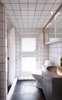 In the bathroom, plain white tiles line the walls and ceiling. The floors are natural stone and the fixtures are by VOLA. Lassen built the sink himself. Photo of A Thatched Cottage in Denmark with a Modern, Space-Saving Interior modern home