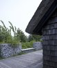 A modern stone fence made of galvanized steel mesh filled with stones surrounds the house. “We got the stones from the local stonecutter—they use the stones washed up on the beach, not the stones from the fields,” Lassen explains. Photo of 30+ Best Modern Fences modern home