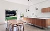 Modern home with Kitchen, Wood Cabinet, and Pendant Lighting. The custom kitchen cabinets sit on legs for easy sweeping underneath. They’re topped with white Corian counters and paired with sleek Brodware fixtures. Photo of A Traditional 1920s Bungalow with a Boxy Modern Extension