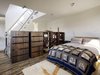 Modern home with Bedroom and Bed. Accessed by a ladder with alternating treads, the sleeping loft features custom casework by Kevin P. Clarke Custom Woodwork that holds Kid Robot figurines, Hopi baskets, and an iPhone gramophone by Lawrence LaBianca. Lights by Pablo Designs are perched atop a bed that Baker designed. Peeking out from under the rug (made by Baker’s mother, Emilie) is a salvaged maple floor, which was finished with VOC-free flaxseed oil. Photo of This Net-Zero Residence Might Be the Greenest Home in San Francisco
