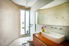 In the upper floor bathroom, streamlined materials highlight the unique and irregular shape of the space. White polished concrete is used for both walls and floors, and frosted Venetian tiles are used in the shower area. Tropical Tzalam wood adds warmth to the space. Photo 6 of Casa Mérida modern home