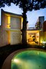 The grand and stately tree is the unchallenged star of the backyard. The round pool, made of made of white polished concrete and handcrafted cement floor tile, smartly pairs with the curved, east-side elevation of the home. Photo 8 of Casa Mérida modern home