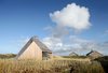 The house is seamlessly integrated into the landscape, at once blending in and sticking out. The exterior cleverly mirrors its surroundings in tone and texture. Solar panels are discretely tucked into the dunes next to the house, and passive building techniques maximize energy efficiency and improve insulation. Wood was favored as both structural and finish material, due to its longevity, recyclability, beauty when aged, and favorable acoustic qualities. Furthermore, since it does not react with salt, wood naturally shields the sea-bordering home from the elements. Photo 2 of Dune House modern home