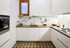 #1 Get things off the counter and consider investing in built-ins.
Since the original kitchen of this Barcelona flat was not functional, the architects built a new one from scratch while preserving the original tiles. “We designed very plain oak cupboards so the floor would be the protagonist,” Eugeni says. Ceiling lamps by Vico Magistretti illuminate the warm wood countertops. A simple shelf with hooks allows storage above and below, and a double-height dish rack grants twice the drying space. Photo of Space-Saving Hacks for Small Kitchens modern home