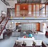 Downstairs, century-old subway tile and copper windows keep the new kitchen gritty; it gained a stainless-steel island, new appliances, and a wall of IKEA storage. Photo of Raw Materials Connect this Chicago Renovation with its Industrial Past modern home