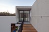 Walking across the pedestrian walkway, residents first glimpse the vestibule leading to the main stairwell. Rectangular patterns mark the concrete garage’s exterior and create a visual rhythm for the 50 foot-long walk to the vestibule. Photo of A Daring Hillside Home Made of Wood, Concrete, and Volcanic Stone modern home