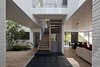 Modern home with Staircase, Wood Railing, and Wood Tread. At the base of the first floor landing, black recinto volcanic stones divide the first floor’s informal dining area from the living room. This floor also features a bedroom and kitchen while the floor above holds a master bedroom, master bath, two bedrooms, two bathrooms, an entertainment room, and patio. The stairs—which are all-oak—descend to a ground-floor playroom and outdoor deck. Photo of A Daring Hillside Home Made of Wood, Concrete, and Volcanic Stone