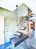 Modern home with Staircase, Metal Railing, and Metal Tread. Futuristic floating stairs lead to the loft’s mezzanine. Throughout the lower level, natural stone was chosen for the flooring, laid at an irregular angle to add visual interest. Photo of A Single-Room Loft with Impressive Wall-to-Wall Storage