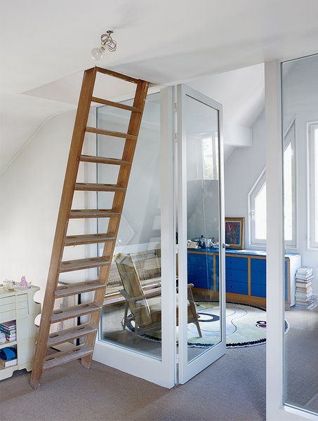 A ladder leads to a guest room in the attic. The striking-blue bedroom dresser was part of a modular storage system installed by the previous owner.