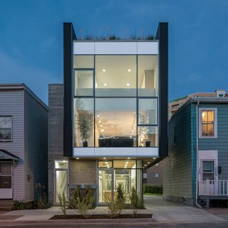 The home’s front façade features an anodized aluminum and glass curtain wall by Kawneer that's framed by Vic West black corrugated metal panels. The board-formed concrete on the exterior enables passive solar absorption, allowing optimal heat retention on cold winter days. The metal and concrete exterior cladding offers cohesive dialogue with the neighboring industrial sheds and commercial buildings.