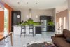 Modern home with Kitchen, Concrete Floor, Subway Tile Backsplashe, Range Hood, Dishwasher, Pendant Lighting, and Refrigerator. IKEA cabinets, Caesarstone counters, and white Dune tiles by modularArts accent the open-plan kitchen. A Viking refrigerator and dishwasher stand near a Capital range. A pair of black Masters Stool by Kartell provide places to sit along the island. Photo of A Fun, Cost-Conscious Home with Bright Interiors and a Climbing Wall