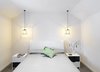 The renovated master bedroom preserves the slope of the original vaulted ceiling. A tufted headboard and suspended Q-BEE steel pendant lights accent the simple and elegant space. Photo 7 of 1850s Prefab Cottage from Boston Finds New Life in Australia modern home