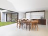 The kitchen is positioned strategically in the middle section of the home’s U-shaped layout. Vintage Bentwood chairs of varying wood tones were chosen for the dining set. The expansive aluminum framed window openings are double glazed in bronze, an eye-catching exterior design note. Recycled messmate timber boards are again used for the kitchen wall and island cladding. Photo 8 of 1850s Prefab Cottage from Boston Finds New Life in Australia modern home