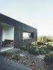 Modern home with Exterior, House Building Type, Concrete Siding Material, Glass Siding Material, and Flat RoofLine. Located on a steep site with limited suitable building ground, the firm decided to cantilever the home over the hillside, which has the effect of helping the structure blend in with the landscape. Photo of Modern House Captures Panoramic Views in Australia