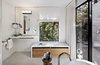 The updated master bathroom features white concrete floors, painted wood walls, and veneer plaster ceilings. Light streams in through the original window, and an added sliding door opens to an outdoor shower. A single Washplane sink by Omvivo sits beneath the mirror, with additional faucets for the shower and Duravit bathtub by Hansgrohe. A stool from Roost holds bath essentials. Photo 8 of Torres House modern home