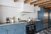 Modern home with Kitchen, Colorful Cabinet, Ceramic Tile Floor, Refrigerator, Ceramic Tile Backsplashe, Range, Vessel Sink, and Drop In Sink. “They knew they wanted a big kitchen where all of their friends could stand around and be involved in the cooking process,” Roberts said of the owners. Exposed beams stripe a ceiling above Wood Mode cabinets painted Newport Green by Benjamin Moore. Photo of Blue Mood: 9 Creative Ways to Use Color