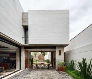 The open and airy courtyard and dining area encourages outdoor living. A custom table made from Andiroba wood and Magis White Air armchairs complete the space.