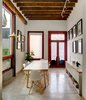In the old building, the painting studio is accessible from the patio. At the center of the space, a custom table is flanked by Eames shell chairs. Tom Dixon pendant lamps hang from rustic wood beams, and a Pablo Studio Lim360 table lamp sits atop a custom white cabinet. Photo 5 of Hybrid Home modern home