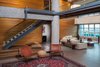 Modern home with Living Room, Chair, and Ottomans. The warped wooden wall backing the living room not only visually counterbalances the coldness of the steel and glass, but also reduces reverbation throughout the entire loft. Photo of A Miami Renovation That Blends Concrete and Rich Wooden Interiors