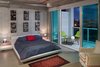 Modern home with Bedroom, Night Stands, Bed, and Table Lighting. Balcony views and large sliding glass doors add to the tranquil airiness of the master bedoom. Photo of A Miami Renovation That Blends Concrete and Rich Wooden Interiors