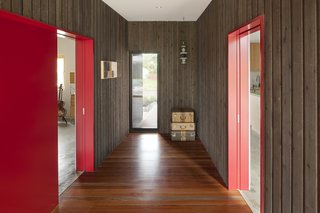 Mahogany flooring, a continuation of the mahogany backyard deck and front porch, is enhanced with a clear finish. Vintage suitcases sit near rough sawn cedar walls, which are finished with an ebony stain.