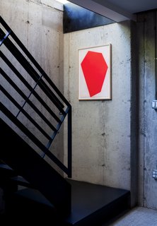 A red print by Cris Gianakos accents a well-lit stairwell leading to a laundry area, library, and rec room on the full basement floor.