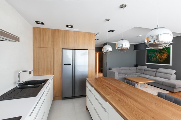 The neutral color palette extends to the kitchen, which is overhung by several pendant globes.