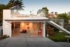 Modern home with Garage, Attached Garage Room Type, Garage Conversion Room Type, and Living Room Room Type. To allude to the nearby ocean, the architects designed a seaweed patterned for the interior of the garage door (seen here raised). It successfully reads like a leather padded wall and makes “the cube” feel that much more customized. Photo of A California Cottage Renovated for Easy Indoor-Outdoor Living